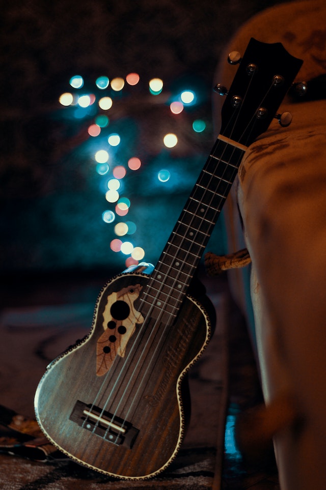 Eine kleine Gitarre ist nachts im Freien an einem Koffer angelehnt.
