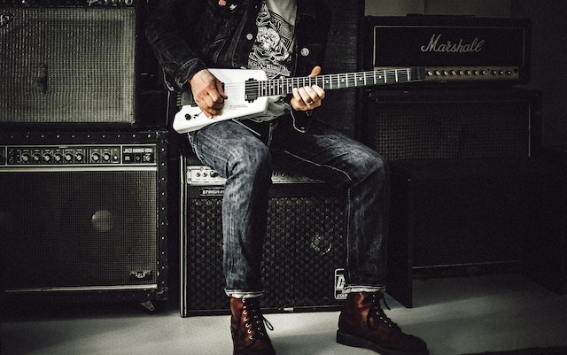 Gitarre stimmen - ein Mann mit braunen Schuhen spielt auf einer weißen Gitarren.